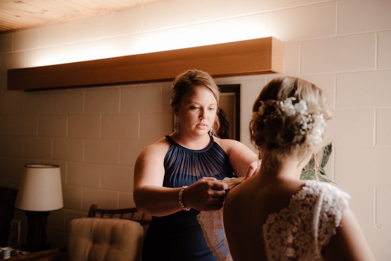 Bride getting help puttin on her dress.