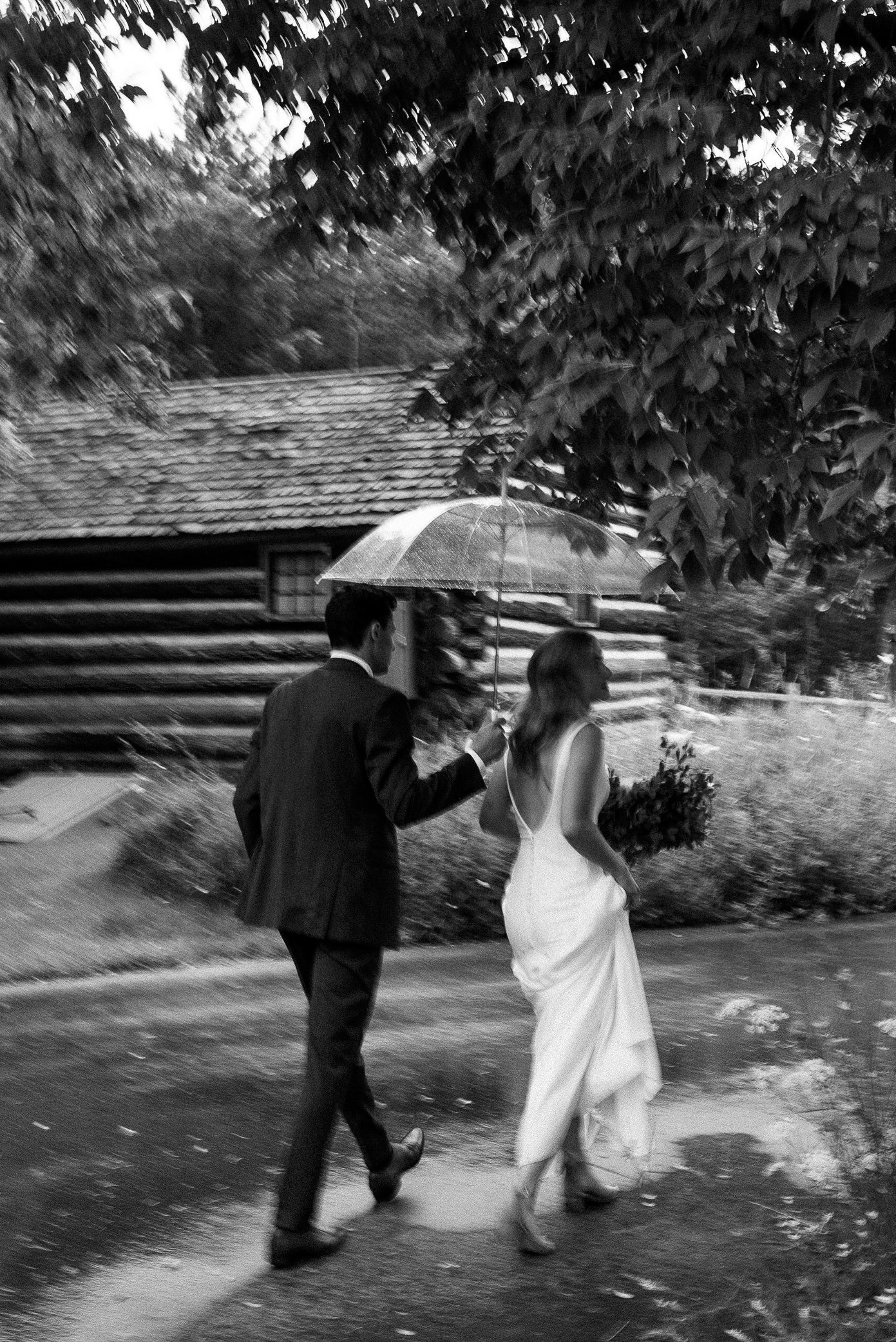 wisconsin bride and groom walking in the rain under an umbrella.