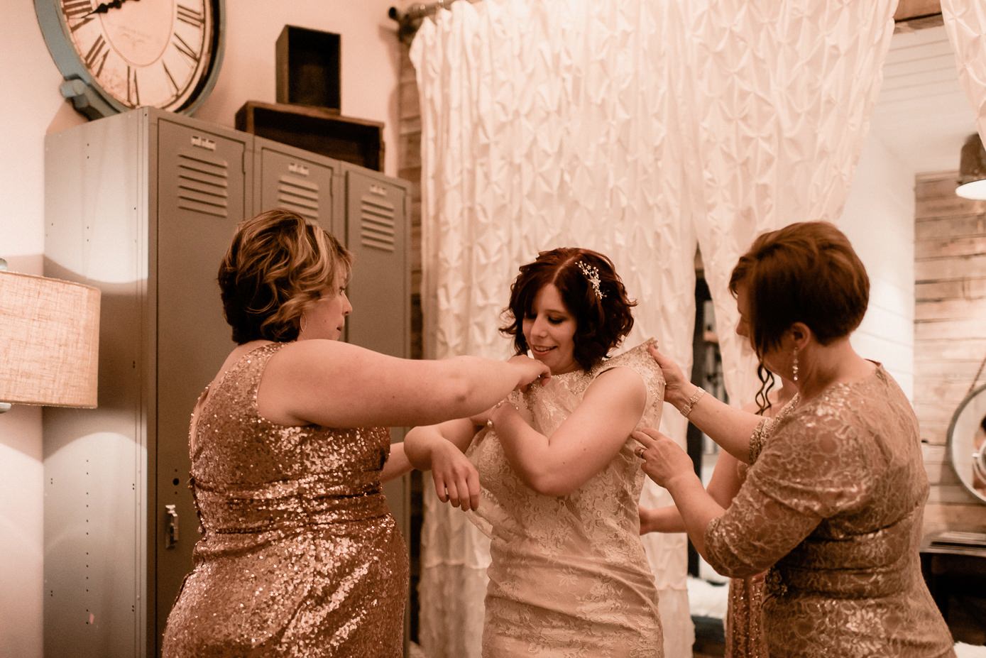 Bridesmaids helping bride into dress