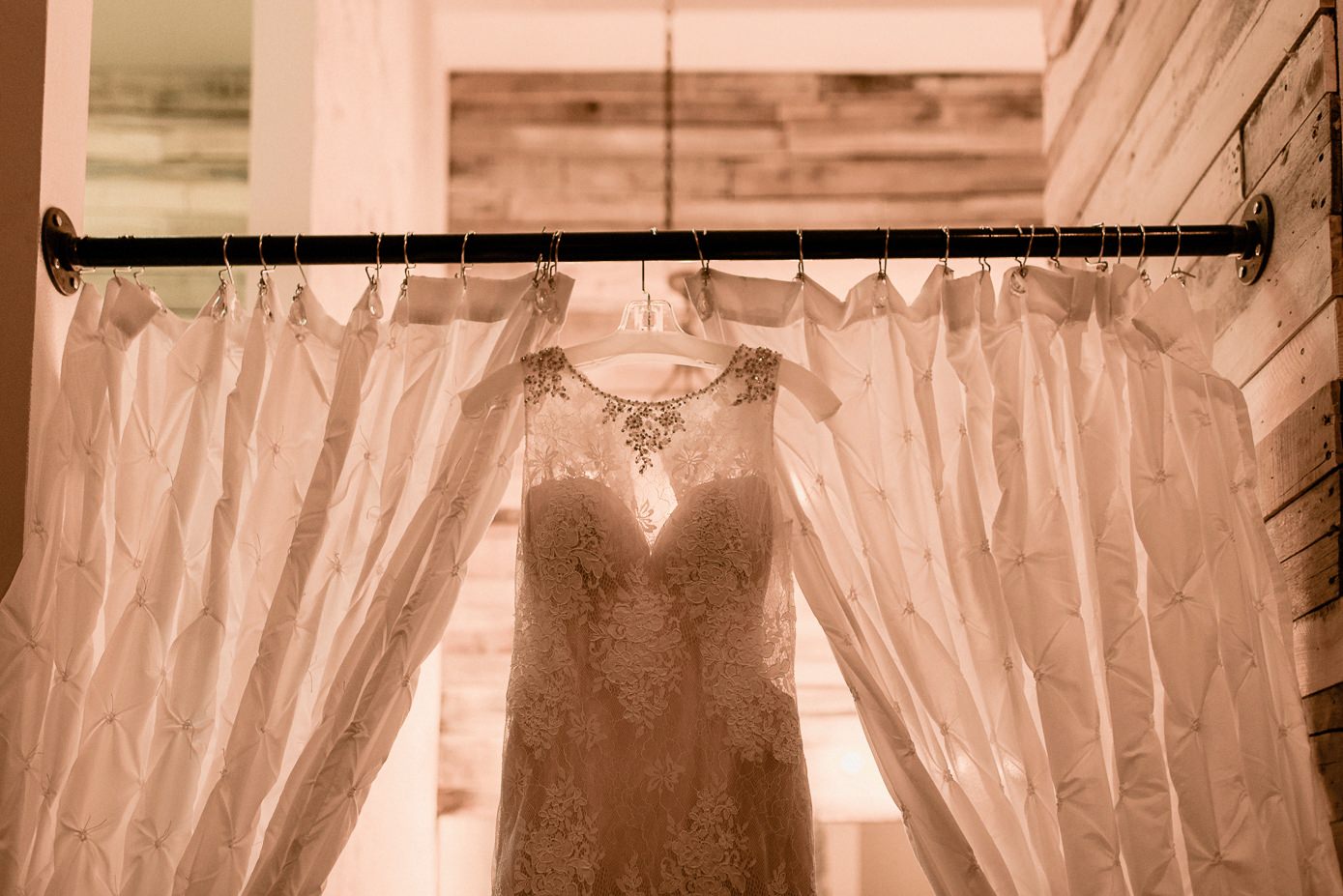 Bridal gown hanging against curtains