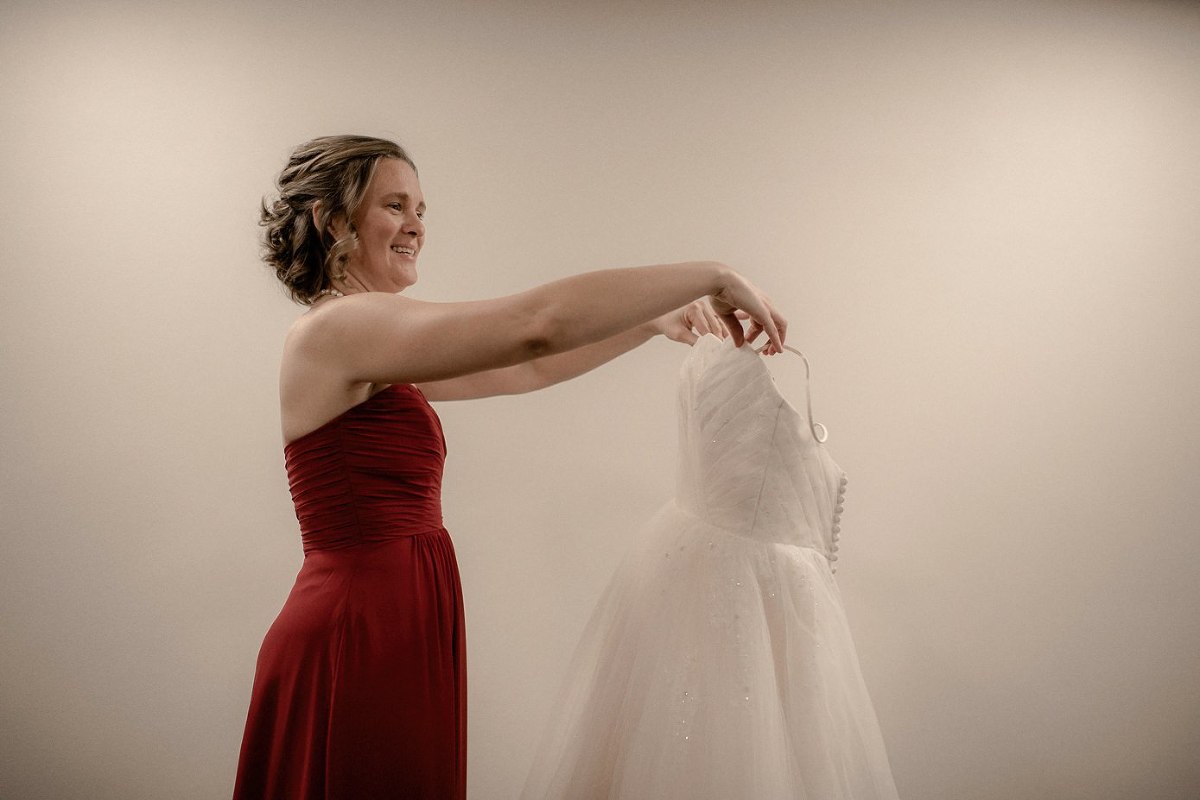 Bridesmaid holding bride's wedding gown