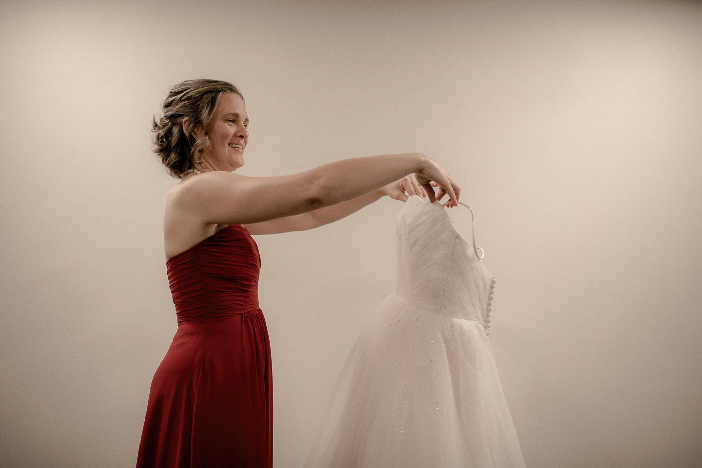 Bridesmaid holding bride's wedding gown