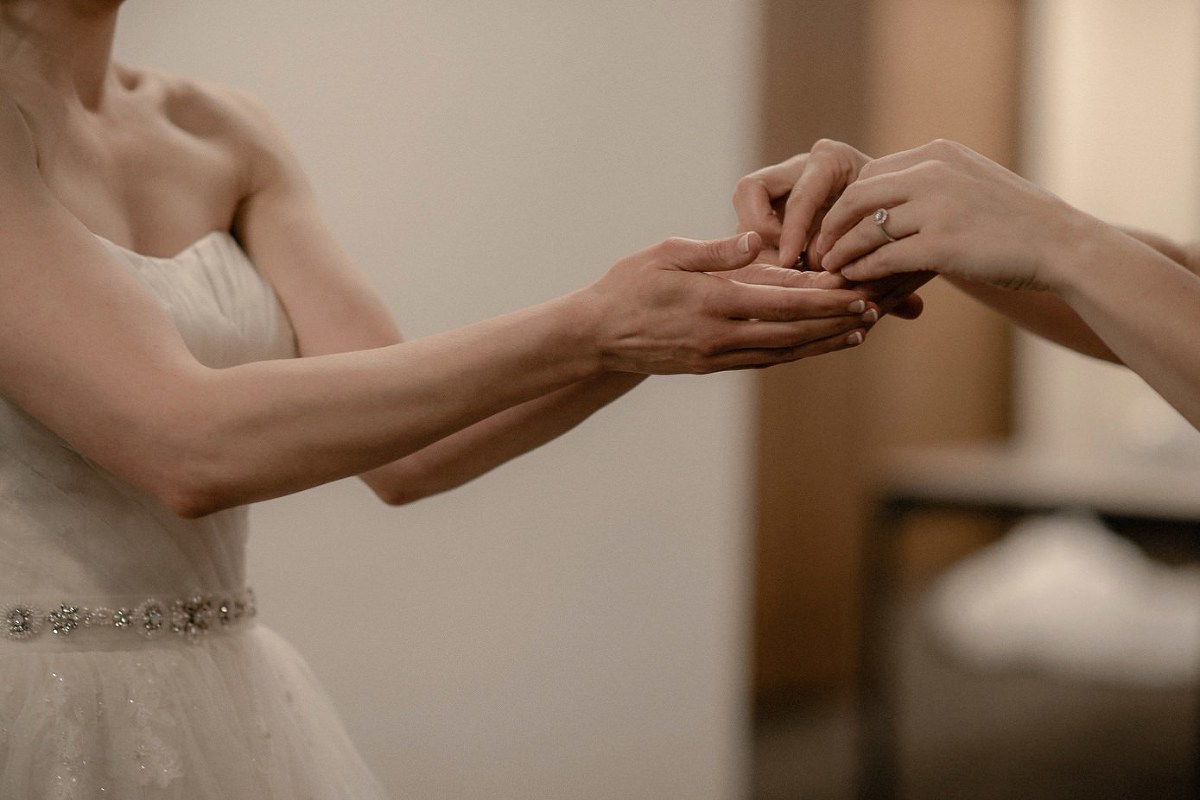 Bridesmaid handing bride her earrings