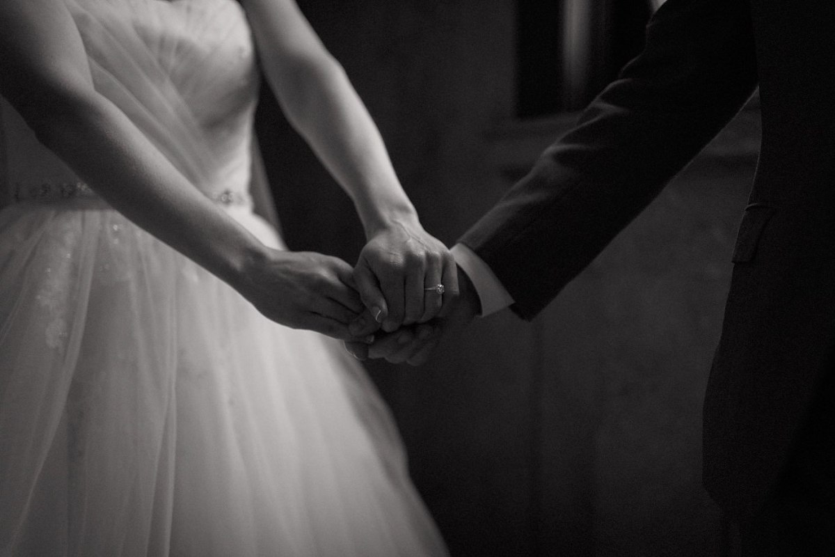 Moody black and white of bride holding grooms hand