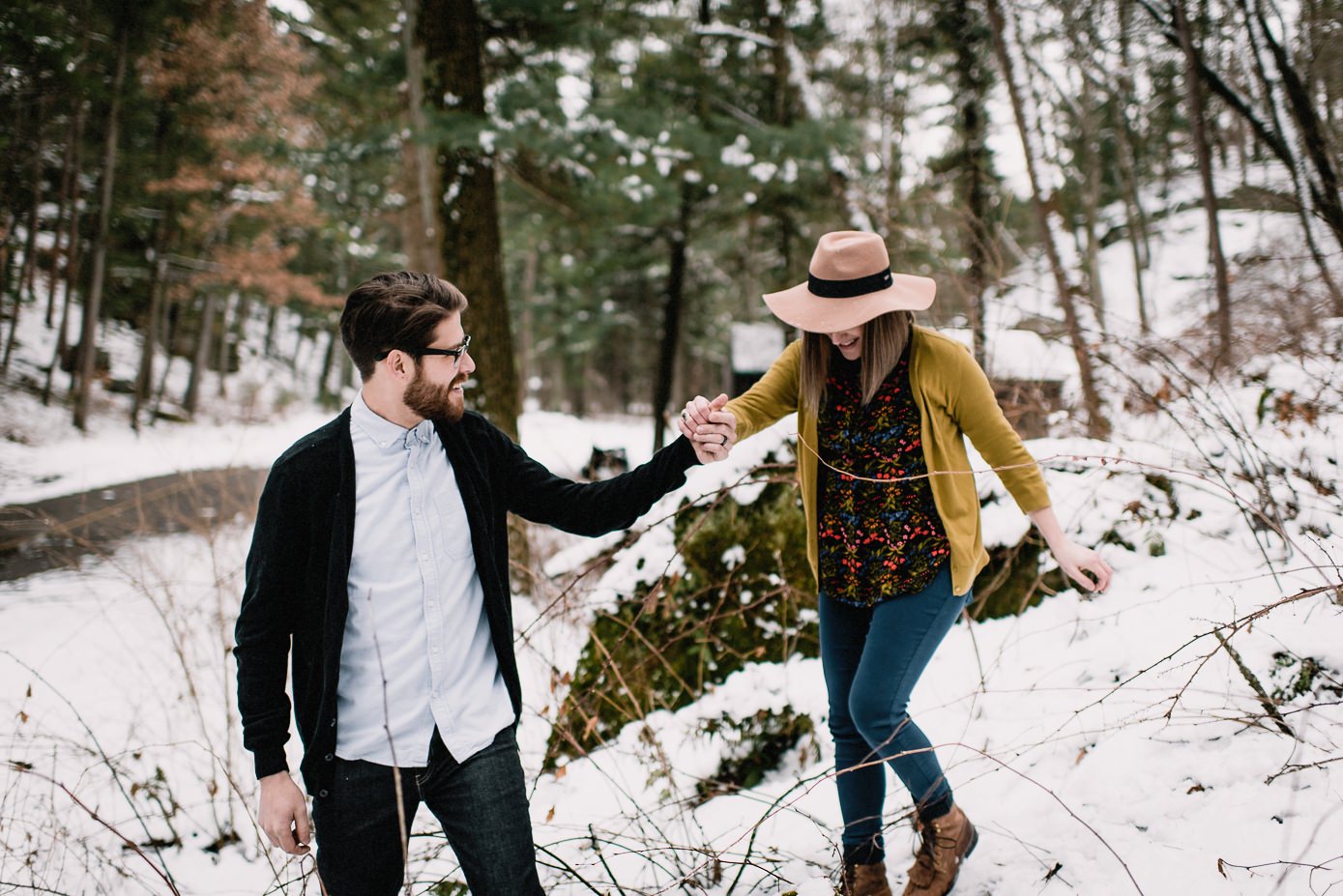 Husband helping wife down snow covered hill