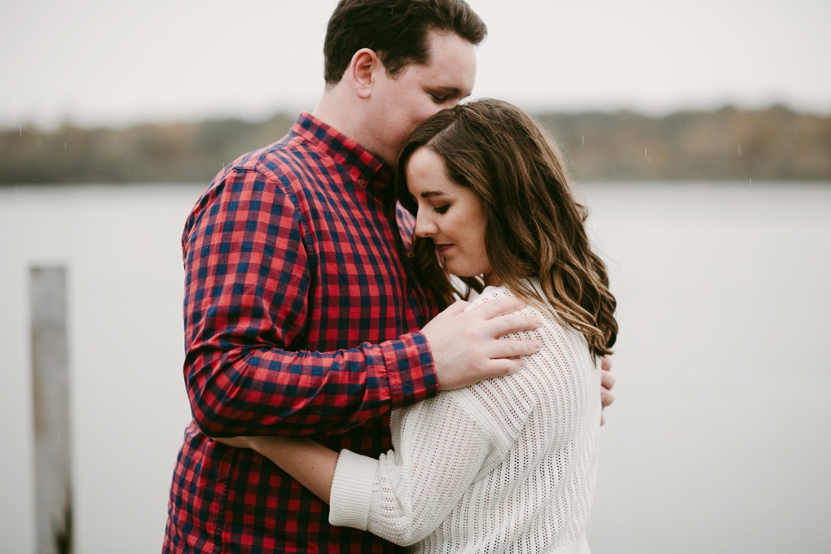Couple snuggling on pier during engagement session at Lake Wingra