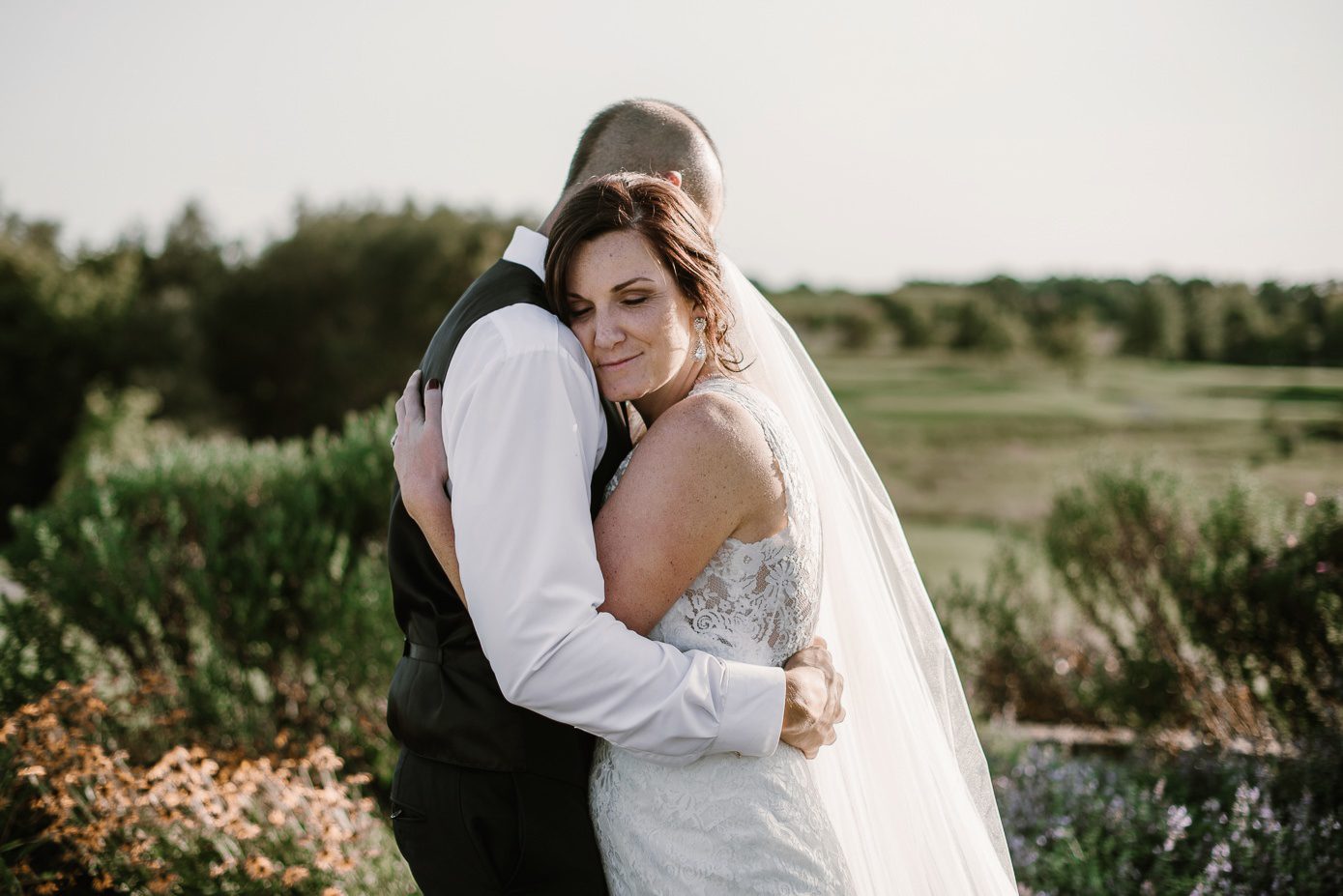 Bride and groom embracing at their wedding at The Oaks Golf Course