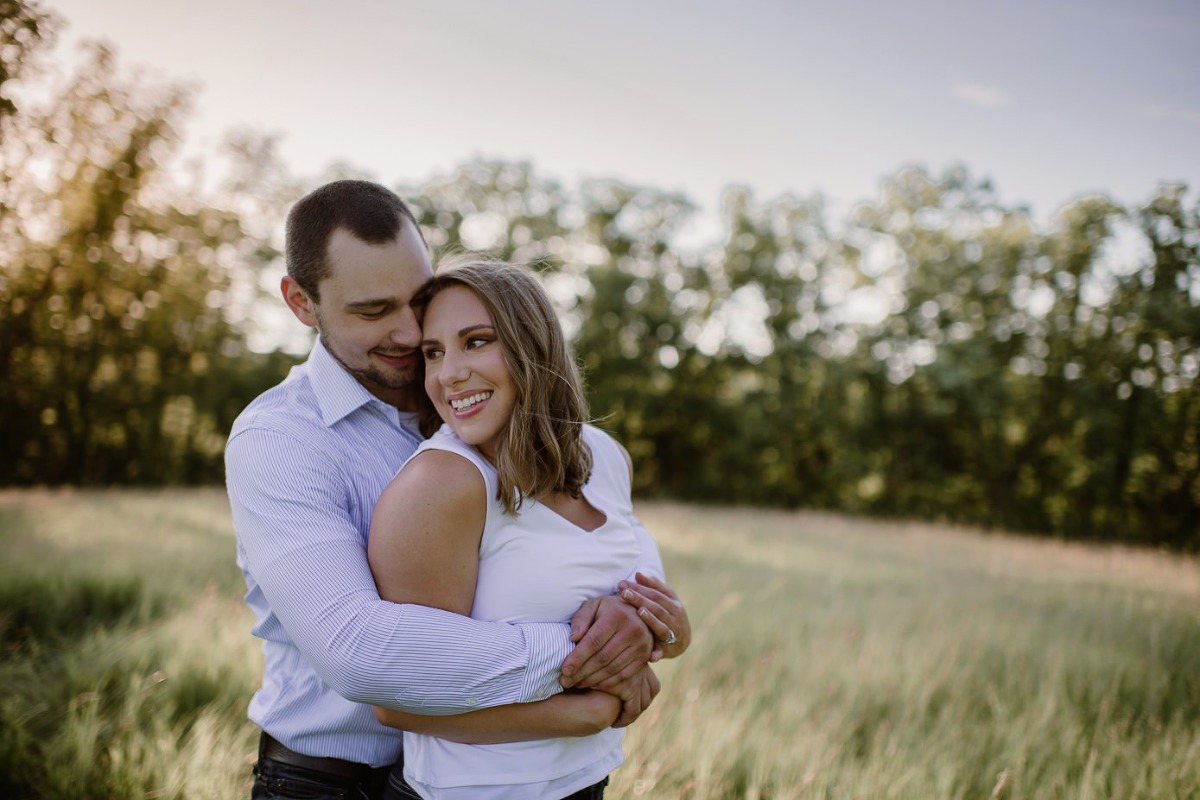 Couple hugging in field during their engagement session