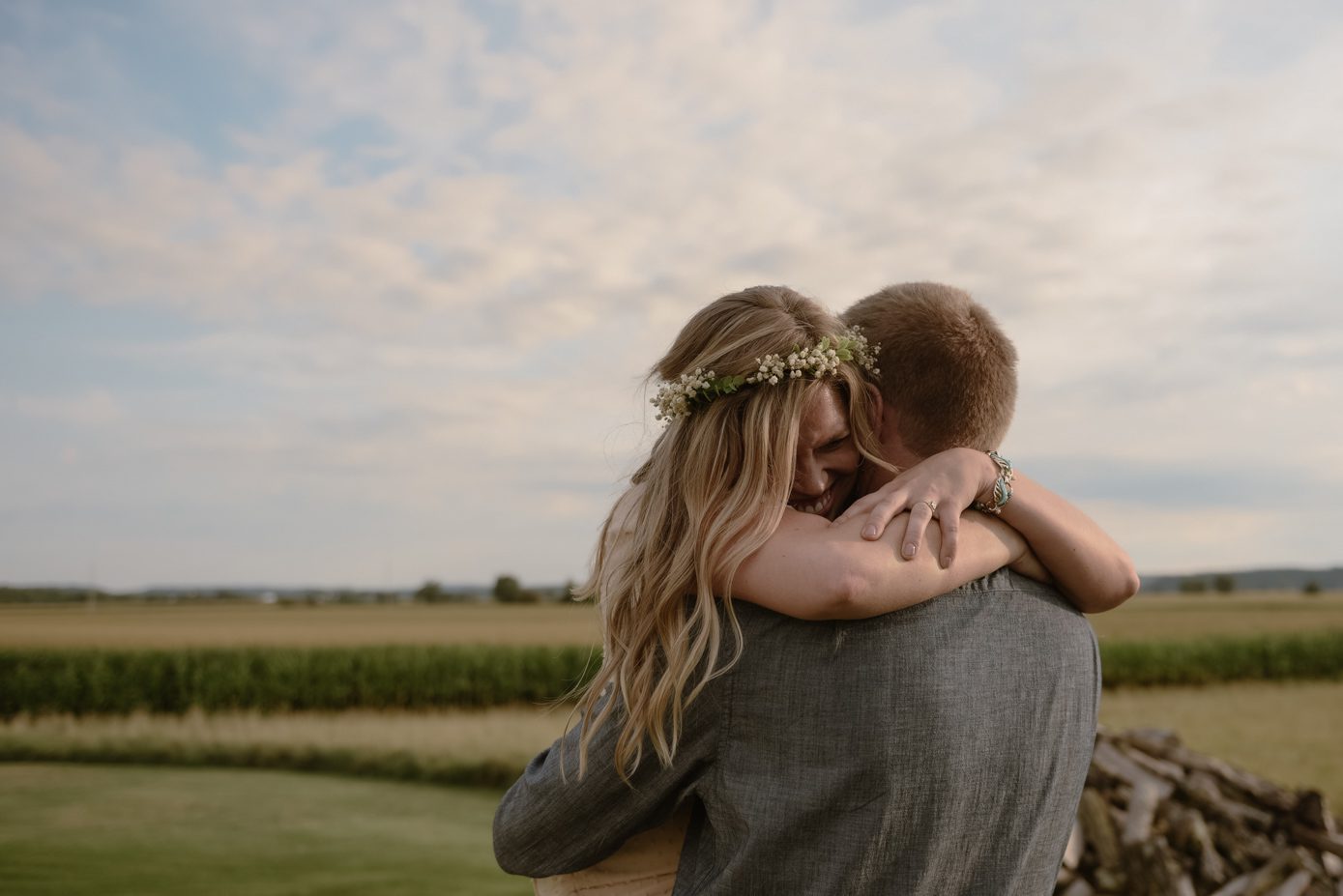 Wedding couple hugging on top of a hill that overlooks cornfields.