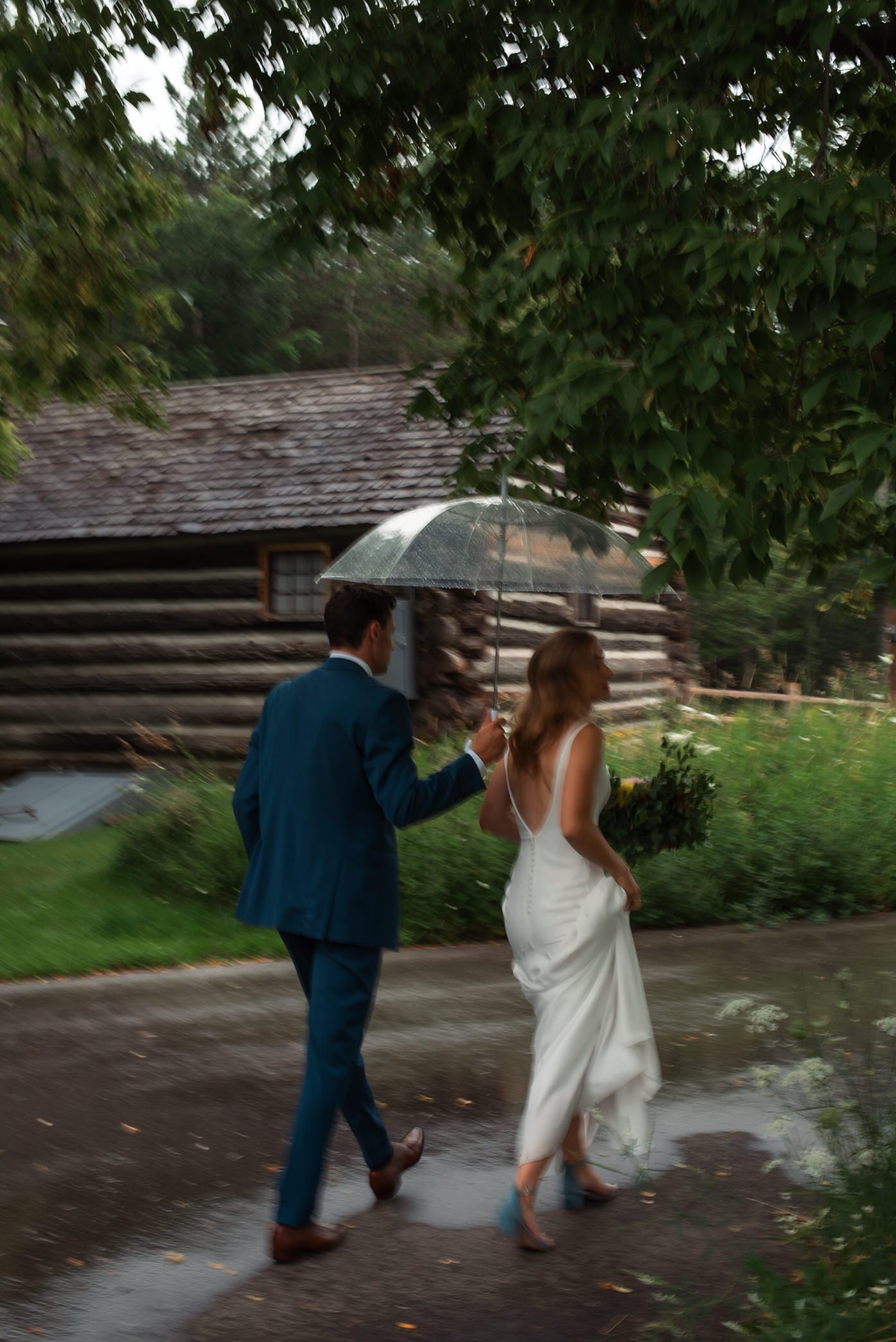 Bride and groom walking in the rain under an umbrella