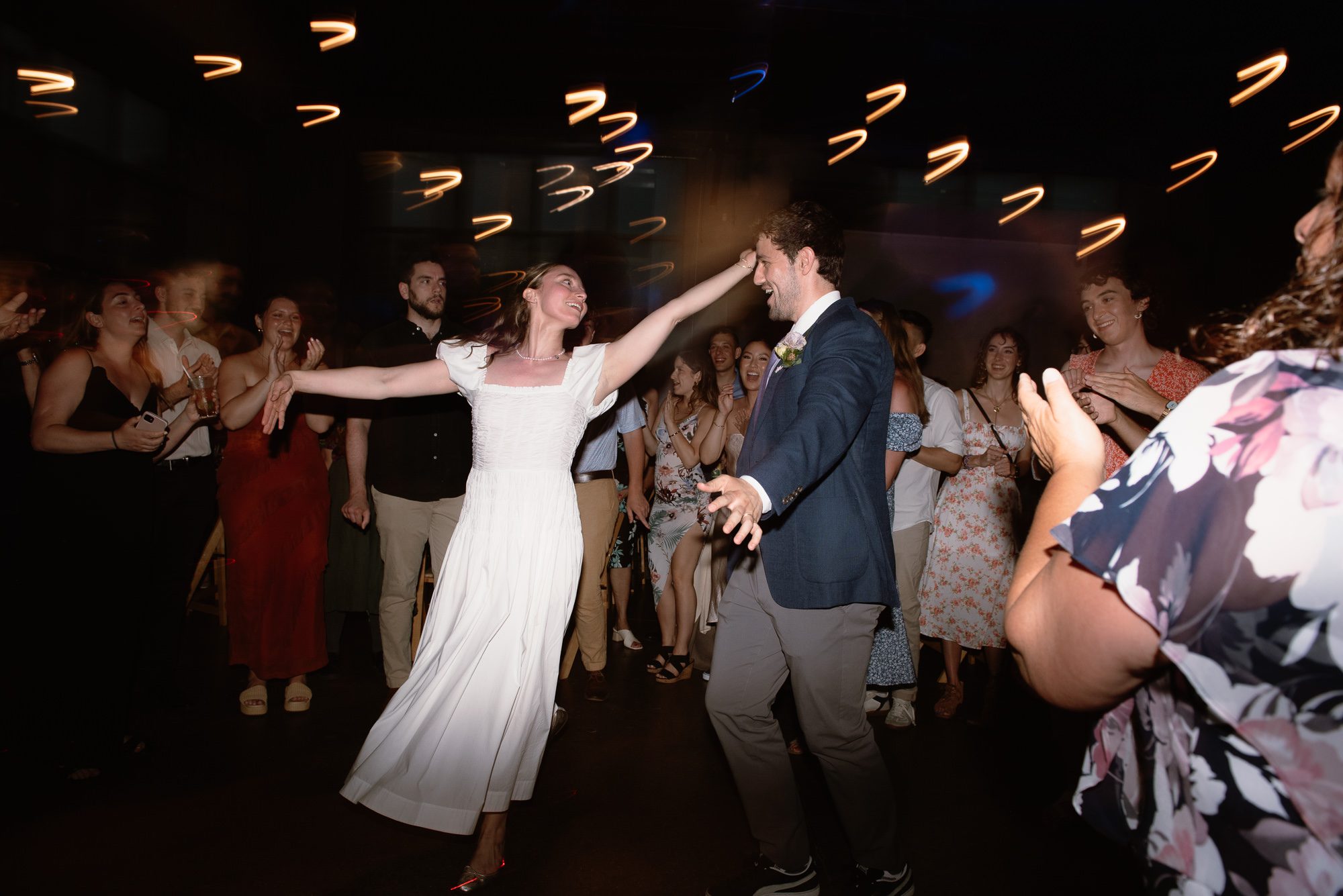 candid photo of bride and groom dancing with guests at old sugar distillery