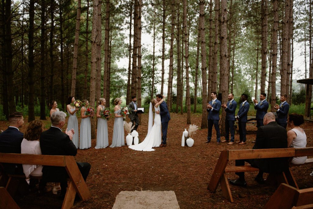 Outdoor Wisconsin wedding ceremony under pine trees at Gordon Bubolz Nature Preserve