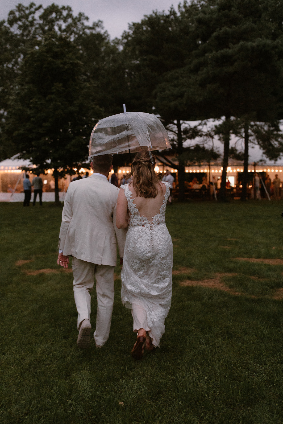 walking to wedding reception in the rain under an umbrella